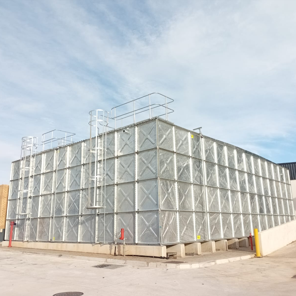 Large rectangular modular steel water tank with safety ladders and galvanized panel construction, installed on a raised concrete base.