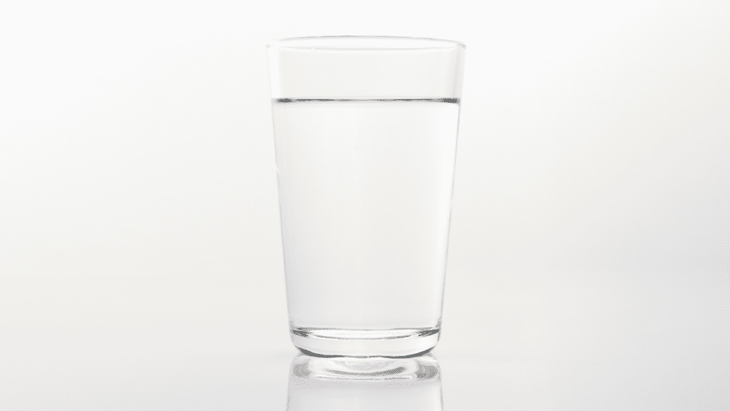 Clear glass of purified borehole water on white background