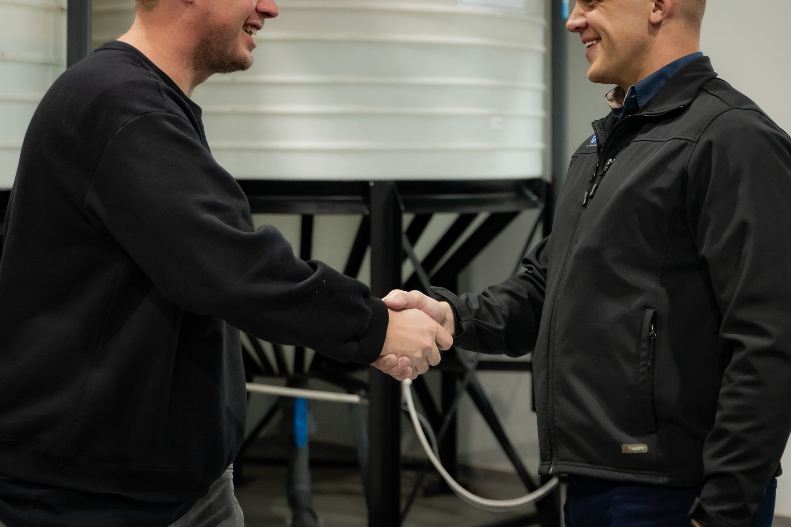iWaterManagement consultant shaking hands with client near water tanks