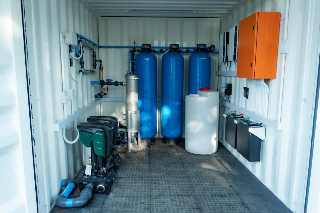 Inside view of containerised water treatment system with blue filtration tanks installed and maintained by iWater Management.