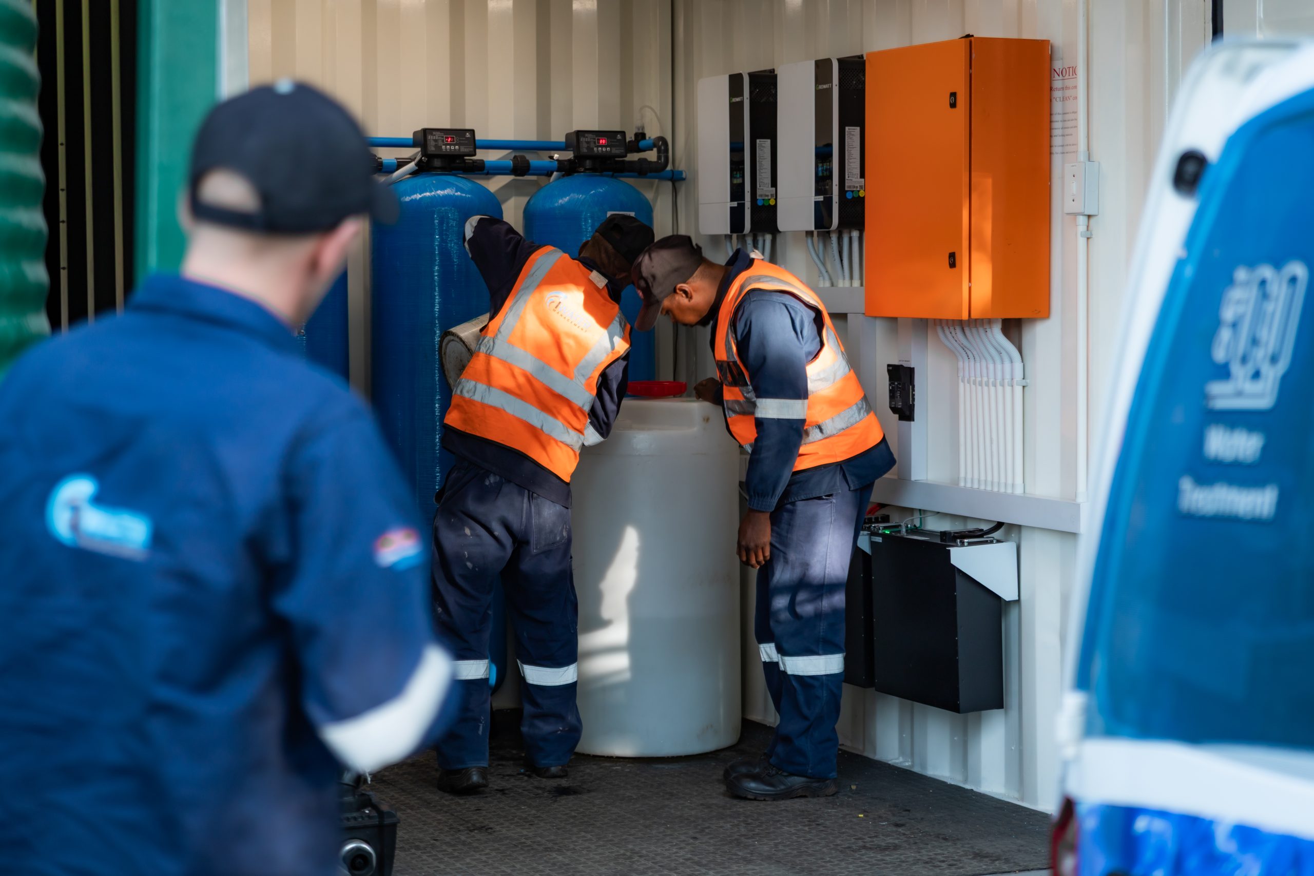 Two iWater Management technicians adjusting containerized water treatment plant components.