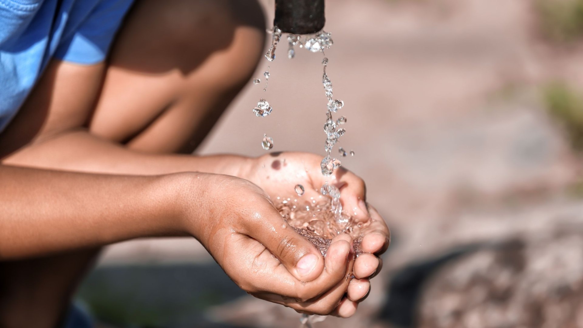 A child's cupped hands holding clean water, representing safe drinking water access in South African schools.