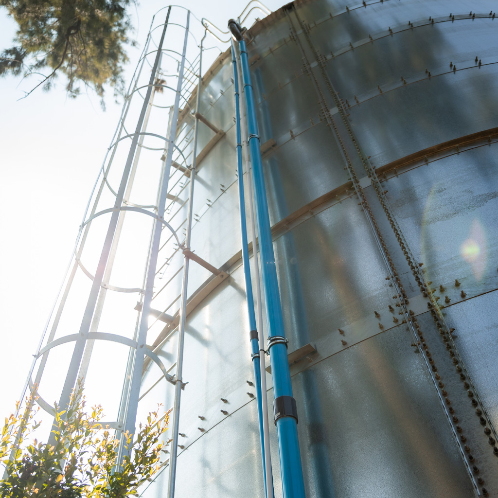 Three types of steel water storage tanks—cylindrical, modular sectional, and elevated—displayed side by side at an industrial facility.