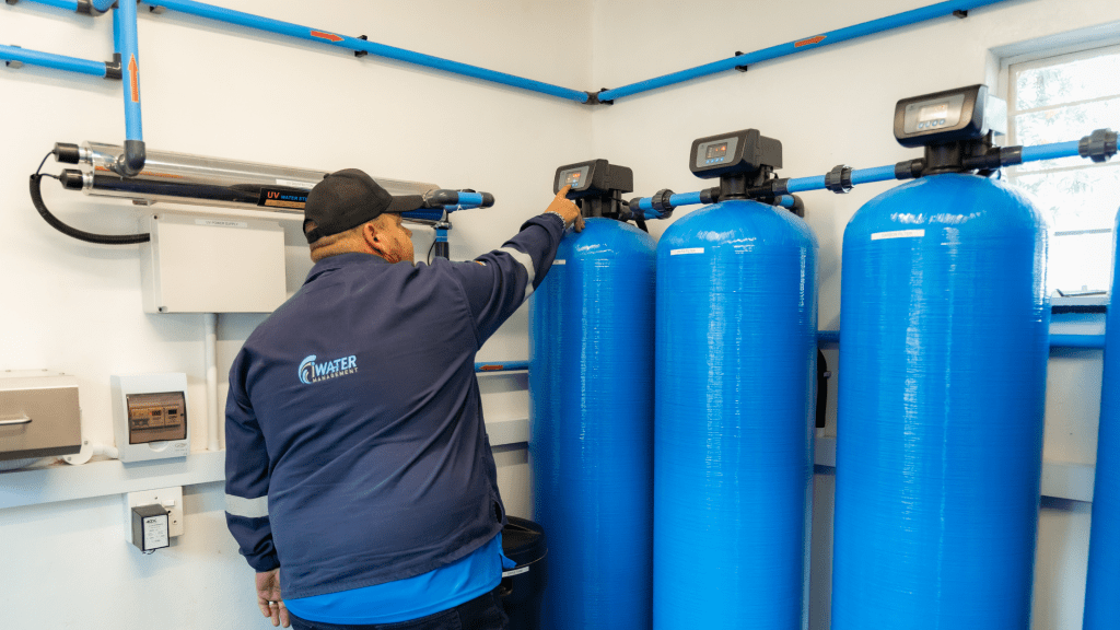 iWaterManagement technician adjusting control valve on a multi-stage blue filtration system in a treatment facility.