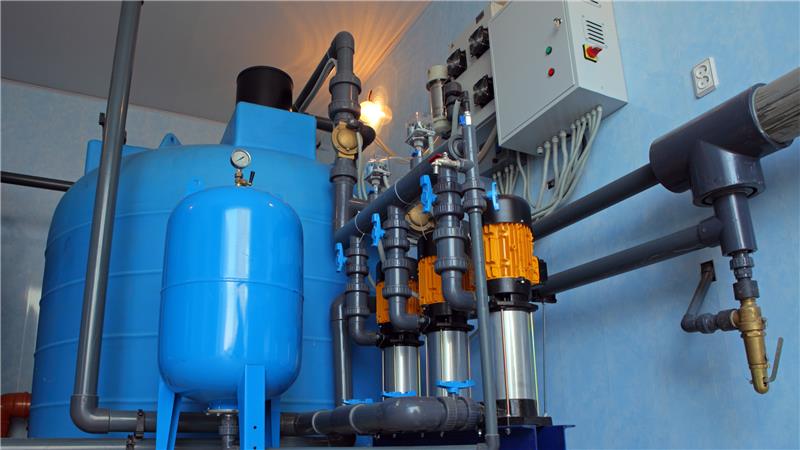 water treatment and purification South Africa, Interior of an industrial water purification unit featuring blue pressure vessels, pumps, valves, and control systems.
