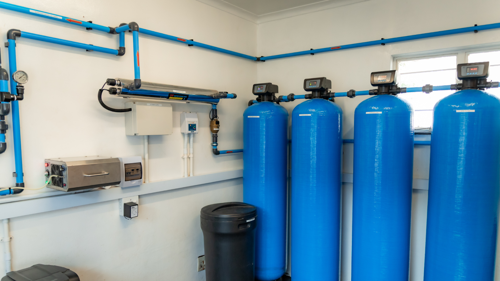 water treatment and purification South Africa, Full view of an indoor containerized water treatment system with multiple blue filtration tanks and a UV disinfection unit.
