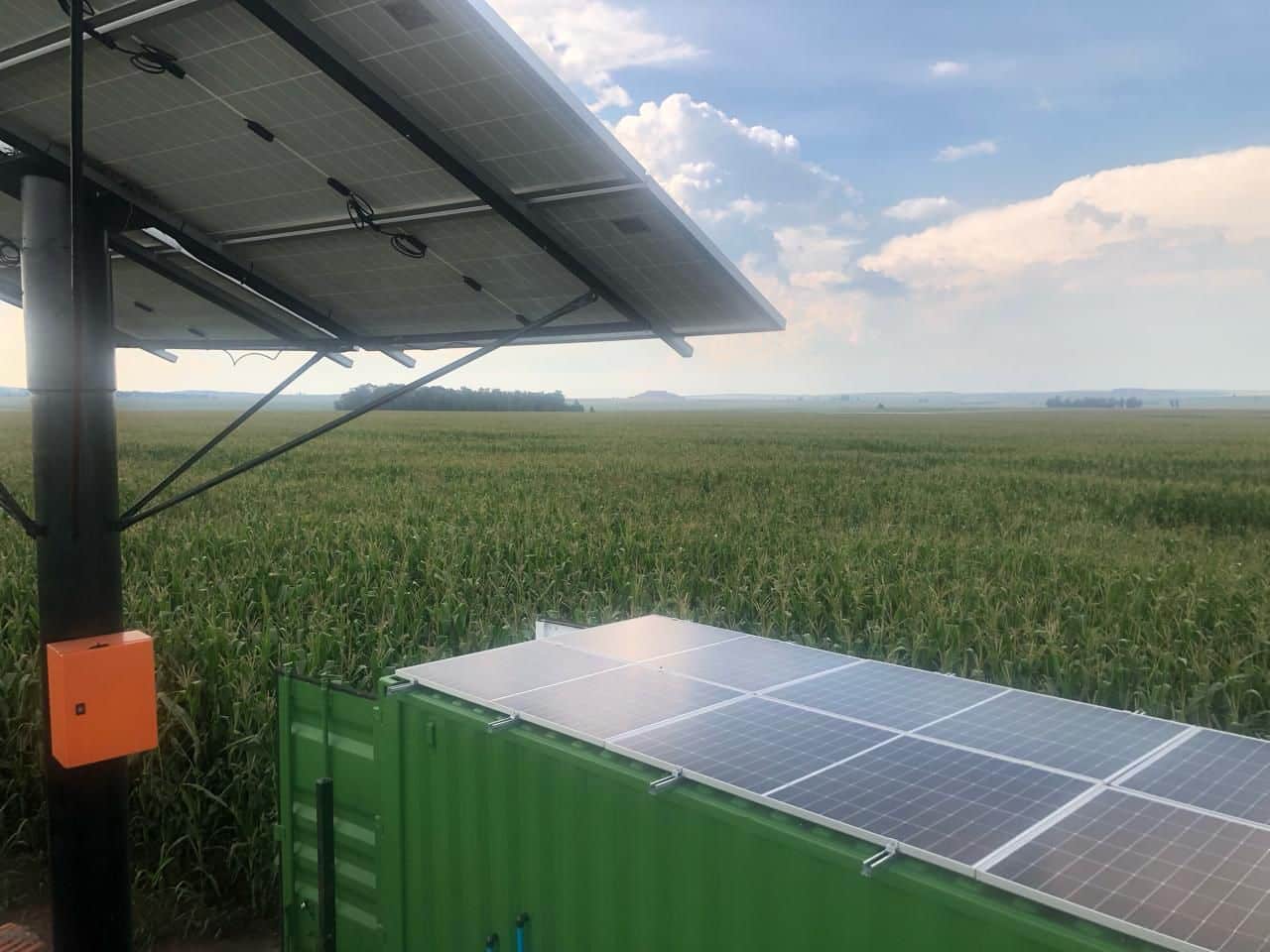 solar-powered-borehole-water-system-agricultural-site.webp Solar panels powering a containerised borehole water system installed beside a crop field for off-grid agricultural water supply.