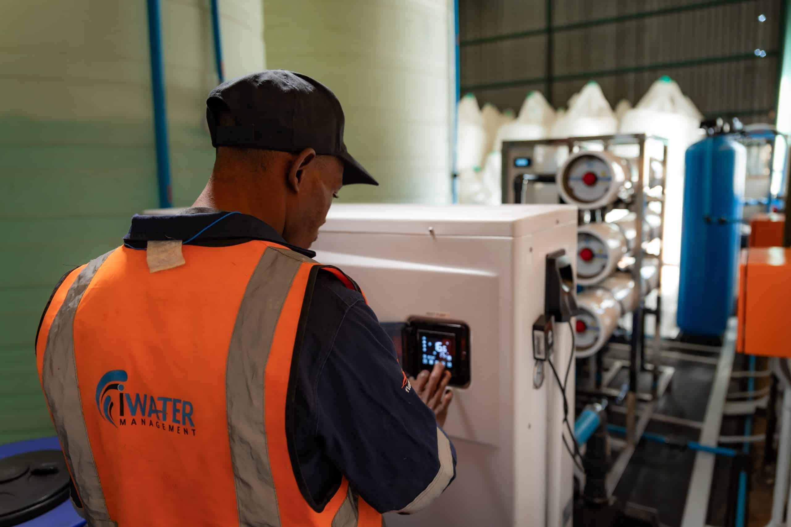 iWater Management technician operating a water treatment and purification control panel with a reverse osmosis filtration system in South Africa.